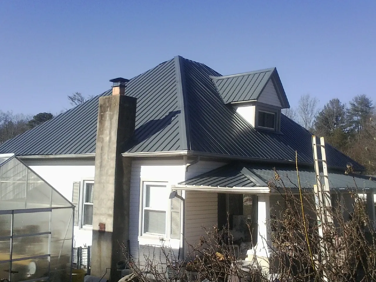 Dark blue standing seam metal roof on a white farmhouse with dormer — Slate & Tile Roof Repair by Roofing Brothers in Cologne