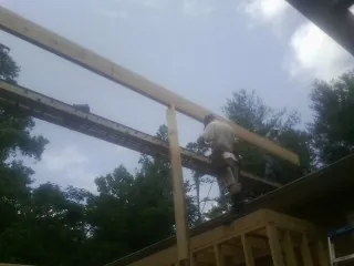 Carpenter setting a ridge beam over a new addition frame — Ice Dam Removal by Roofing Brothers in Cologne