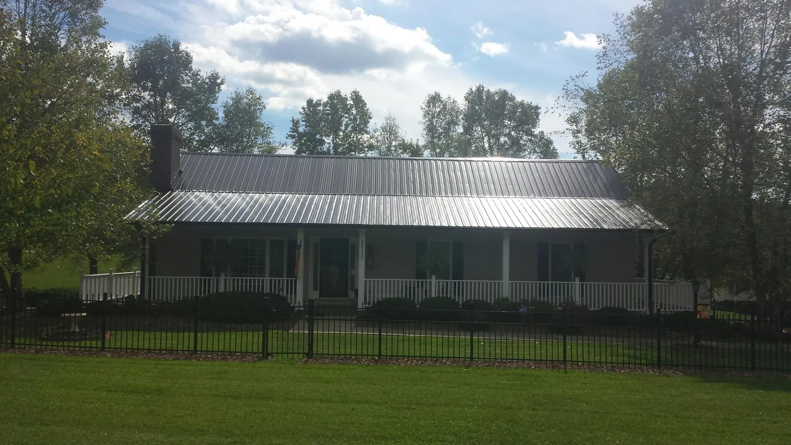 Gray metal roof on a brick ranch with a full width front porch — Gutter Guard Installation work by our crew in Cologne