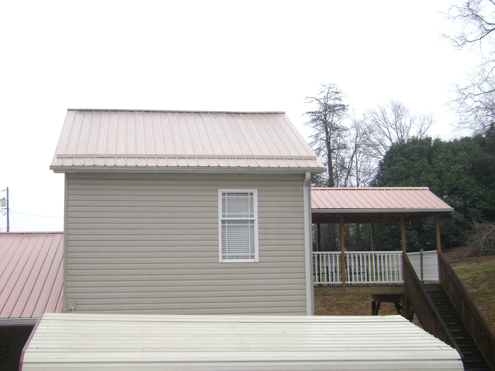 Tan metal roofs on a two story addition and attached porch, from a Roof Replacement job in Cologne