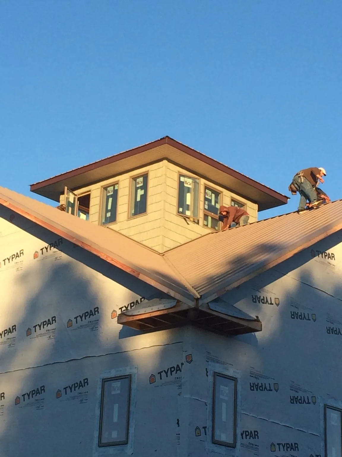 Roofers working around a rooftop cupola on a new metal roof at sunset — Roof Waterproofing in Cologne by Roofing Brothers